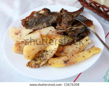 Greek taverna style baked lamb and potatoes, the lamb cooked on the bone and the potatoes sprinkled with oregano