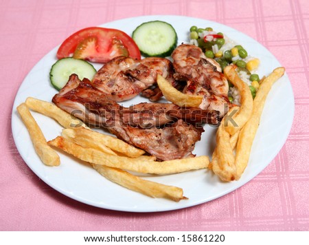 A grilled rabbit, served with french fries, rice and vegetables in a taverna restaurant. Rabbit is a favourite meat for the Greeks.