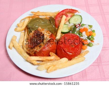 Traditional greek stuffed vegetables (gemista) served by a taverna restaurant with french fried potato chips, rice and vegetables.
