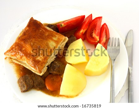 A meal of steak pie, with a puff pastry crust, viewed from above