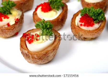 A plate of quails\' egg canapes, the eggs are in tiny baked jacket potatoes, topped with lumpfish caviar and a sprig of english parsley