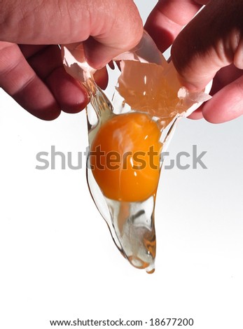 Hands breaking an egg to add to cooking