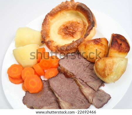 Traditional British Sunday dinner of roast beef and Yorkshire pudding, with boiled and roasted potatoes and boiled carrots