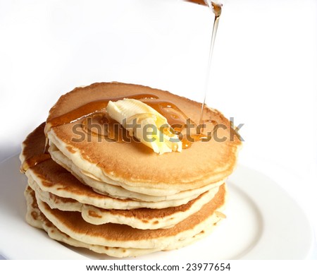 A pile of pancakes with a dollop of butter and maple syrup being poured over them