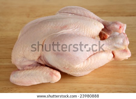 A raw chicken waiting to be prepared on a kitchen chopping board