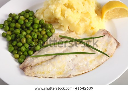 A healthy meal of baked fish with mashed potatoes, boiled peas and a wedge of lemon