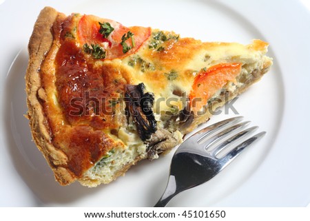 A slice of homemade mushroom quiche on a white plate with a fork, viewed from above