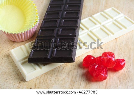 White and dark chocolate, cherries and cups for cakes on a chopping board, ready for cake-making