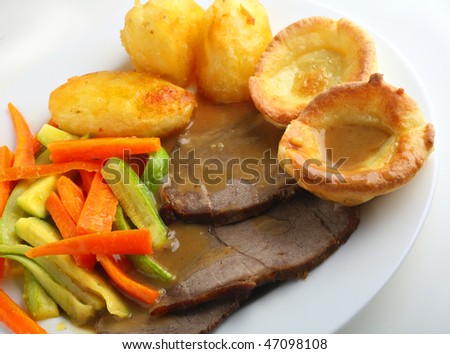 Traditional English meal of roast beef and yorkshire puddings (popovers), with julienned courgette (zucchini) and carrots, oven roasted potatoes and gravy.