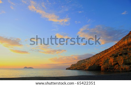 Sunset over Matala beach, Crete, with Roman era graves cut into the cliffs on the left. A small community of dropouts and drifters still live in the caves