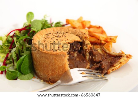 A raised steak pie, served with french fried potato chips and a green salad.
