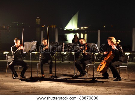 DOHA, QATAR - JANUARY 8: A string quartet performs against the backdrop of the Arabian Gulf and an Arab dhow as part of Qatar\'s celebration on hosting the Asian Cup, January 8, 2011
