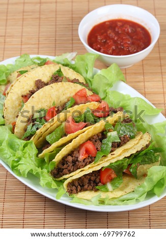 Tacos on a bed of lettuce on a serving plate