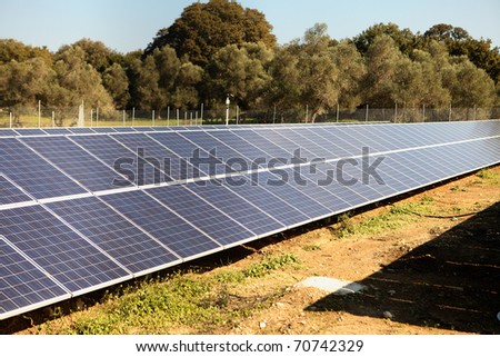 An array of solar panels on the island of Crete, Greece, with an olive grove in the background