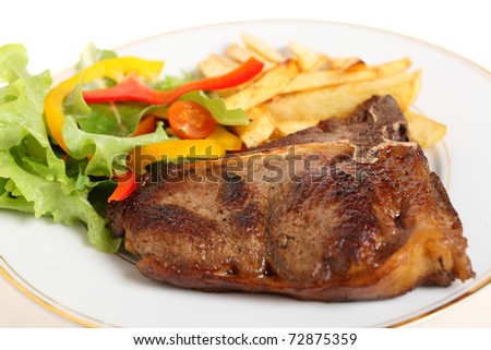 A meal of pan-seared T-bone steak with french fries and a salad of lettuce, rocket, capsicum slices and cherry tomatoes