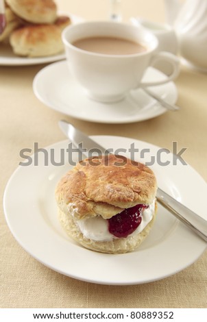 A traditional English cream tea, with scones, strawberry jam and whipped cream, served with tea and milk
