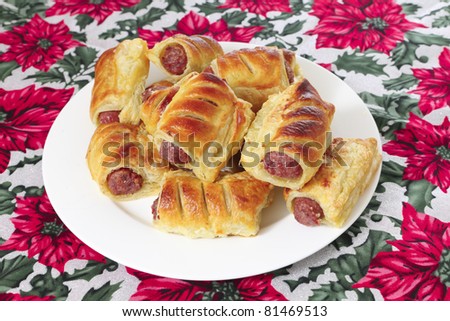 A plate of sausage rolls, traditional British Christmas food, on a festive tablecloth