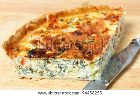 Horizontal view of a quarter of a delicious quiche made from spinach beet (aka Swiss chard or sea kale beet), leek and tomato baked in a cheesy egg custard