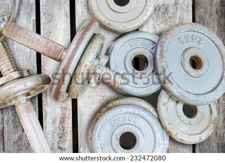 Fitness equipment dumbbell weights on old wood background
