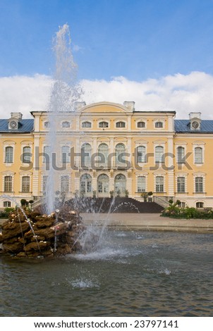 Fountain in foreground of entrance in yellow baroque palace