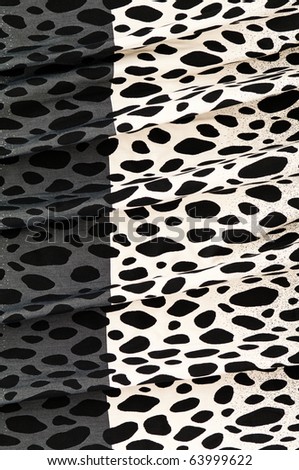 Folded textile background with black and white cow pattern