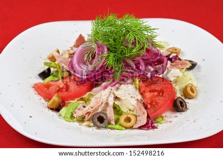Salad of lettuce, tomato, chicken meat, olive, greens, onion