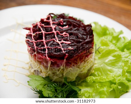 Tasty fresh healthy salad with herring on wooden table background. Russian dish.