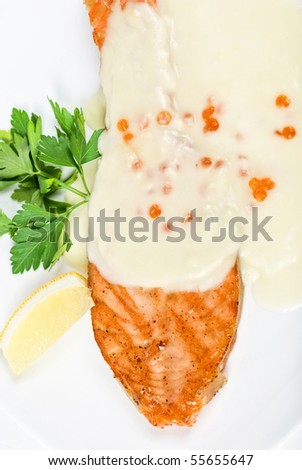 Grilled salmon steak with cheese sauce, greens, lemon and red caviar
