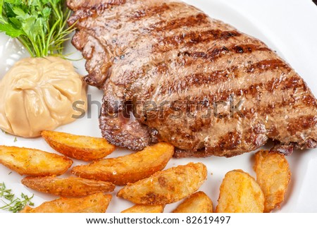 Juicy beef steak stuffed with beef tongue and cheese served with potatoes, greenery and sauce