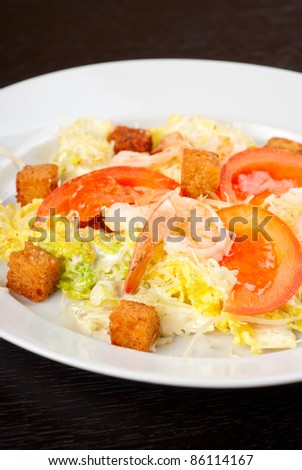 Salad of tiger shrimps, lettuce, chinese cabbage, tomato, garlic rusk, parmesan cheese and sauce