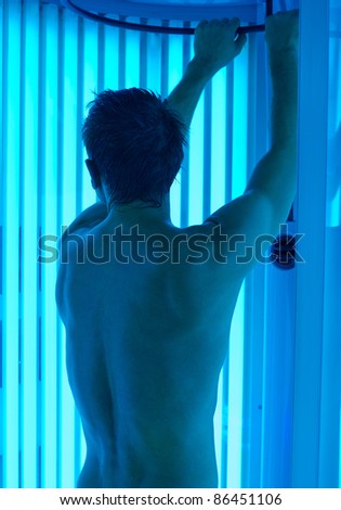young man closeup at tanning solarium light on