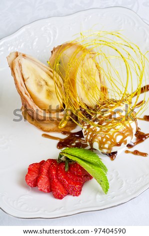 Dessert of pancake with banana, ice-cream, caramel, strawberry and mint