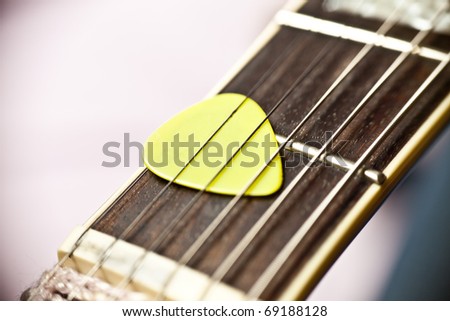 Guitar pick between strings of a fretboard