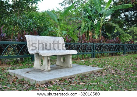A solitary stone bench for park visitors to sit and relax, banana tree in background