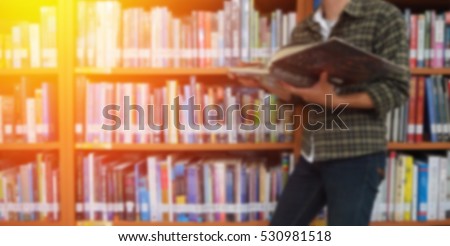 Reading book and abstract blur bookshelf in library room background
