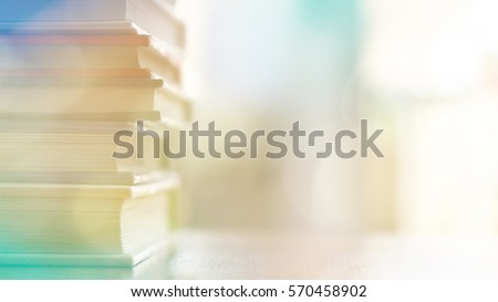 Book stack on wood desk in the library room and soft focus with bright light, education and business background
