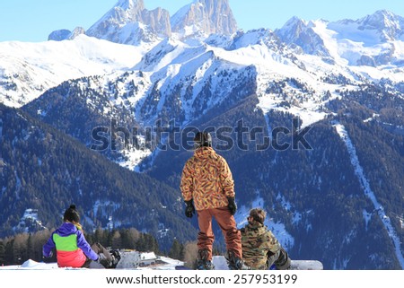 Three snowboarders in bright clothes on a background of mountains