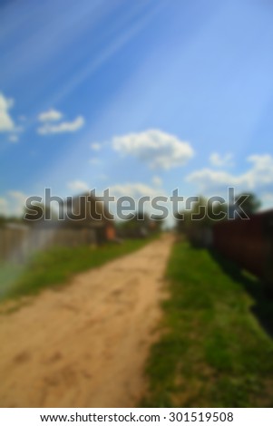 blurred background, bokeh background, dirt road, green grass, houses in the village, blue sky, summer