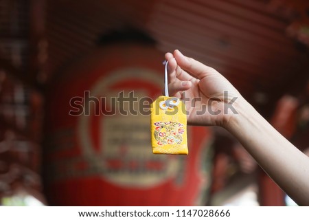 Japanese lucky charm. A hand holding a yellow omamori or A Japanese lucky charm to grant a wish fulfillment