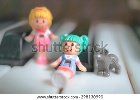mini toy figurines of little girls and a pet dog on Piano Keyboard. Soft Focus, Soft and Dreamy Effect.
