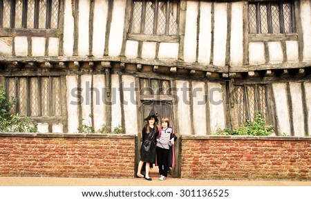 LONDON - SEPTEMBER 4, 2012 : 2 kids in Witch & Wizard Costumes standing in front of the replica of Potter's Cottage in Godric's Hollow, at Warner Bros. Studio Tour London - The Making of Harry Potter.
