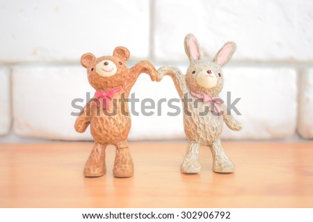 Soft Focus of Ceramic Bear and Rabbit Raising Hands in heart shape, Soft Focus on Rabbit, Blur Background, Love and Happiness Concept [Sweet Pastel Collection]
