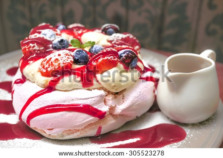 Merinque with fresh cream and homemade berry sauce serve with fresh berries