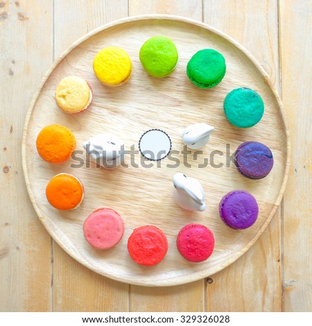 12 Colorful Macarons on the wooden plate with blank logo in the middle and mini ceramic rabbits, replica as a clock on the wall