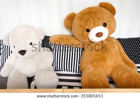 Big Teddy Bear Plush Dolls sitting together on the sofa with black and white stripe pillows, relax and cozy concept
