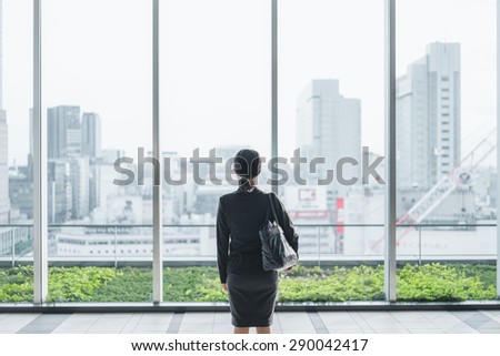 Business woman sees a large city from big window pane