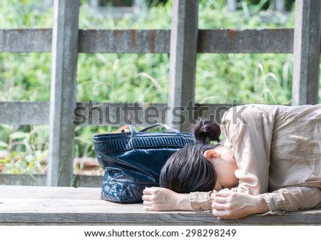Asian woman lying down on park bench