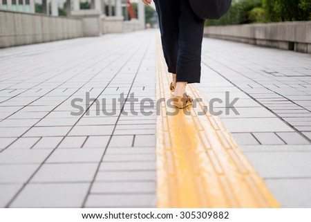 Asian woman walking on tactile paving
