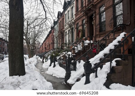 Typical brownstone row houses in Brooklyn. Street covered in snow