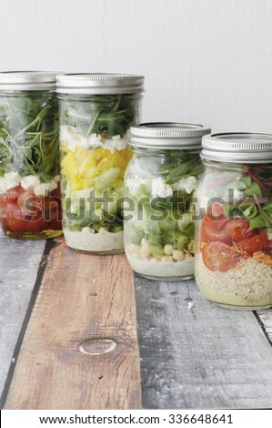Lunch salads in mason jars  on wooden surface
